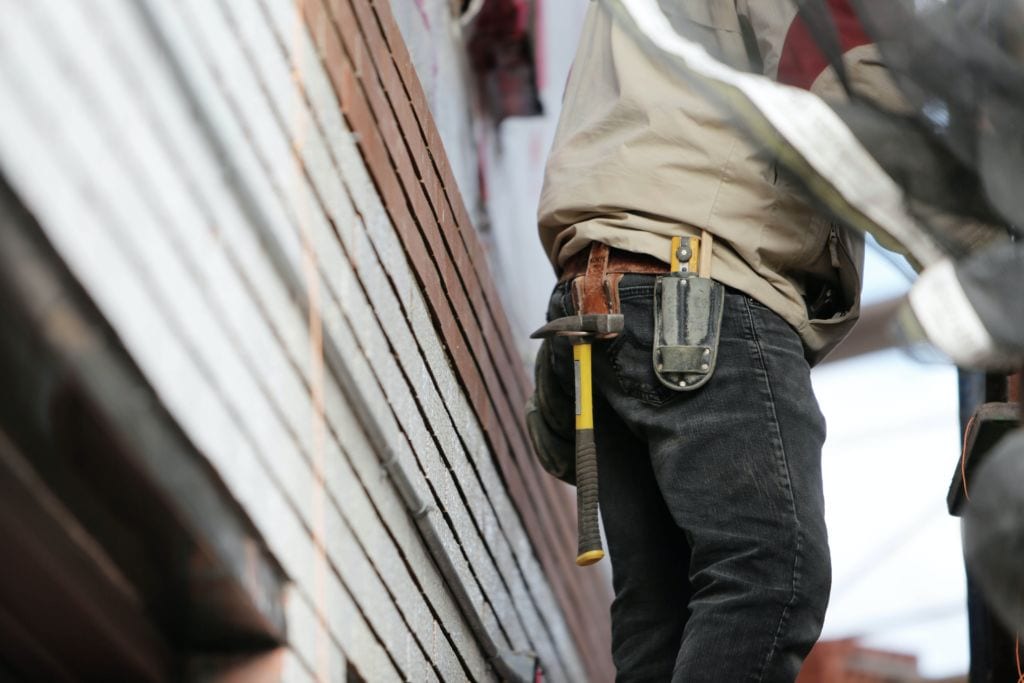 Close Up Of Roofing Contractor Next To Home