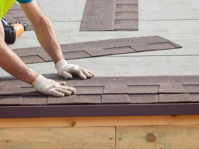 Roofer builder worker installing roof shingles