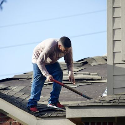 Roofer removing damaged shingles