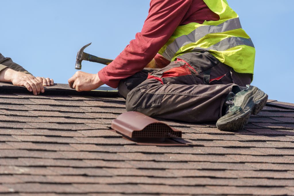 Roofer nailing down shingles