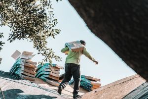 man on roof carrying materials