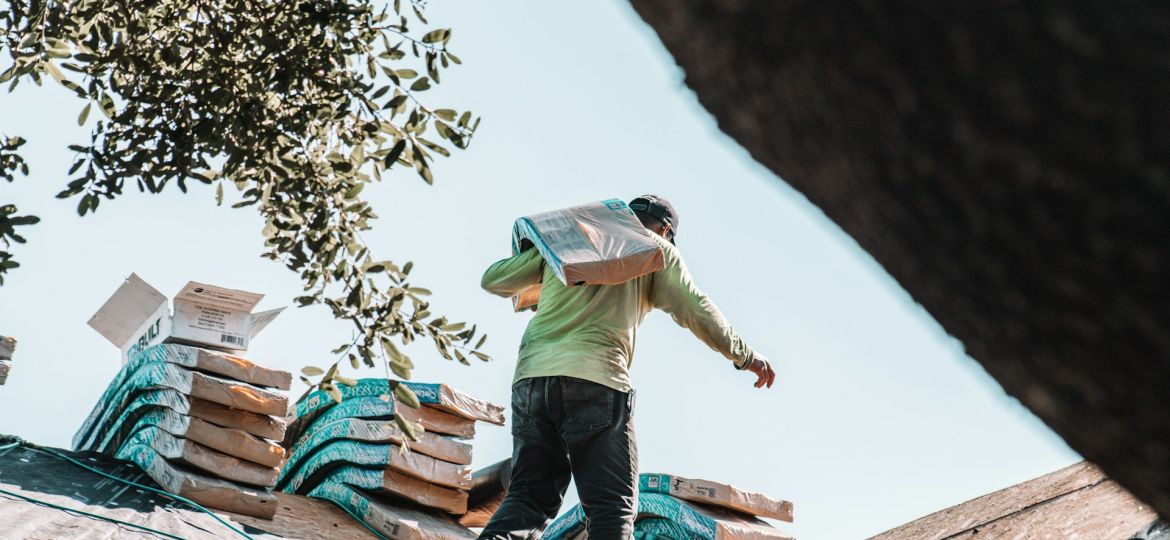 man on roof carrying materials