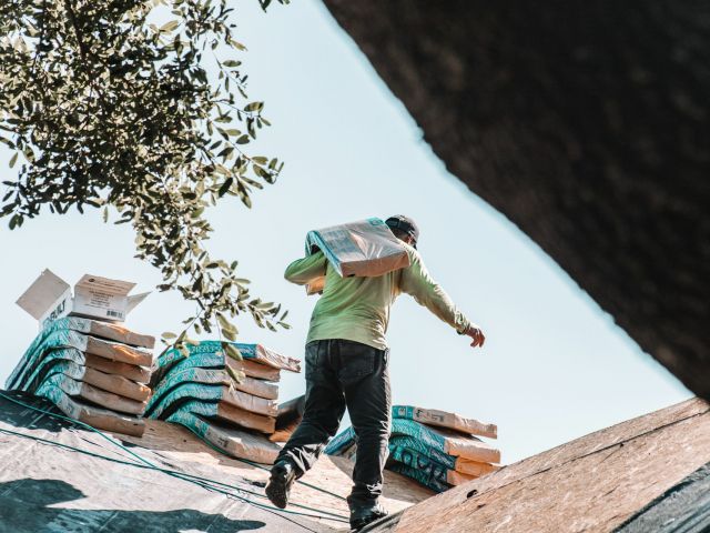 man on roof carrying materials
