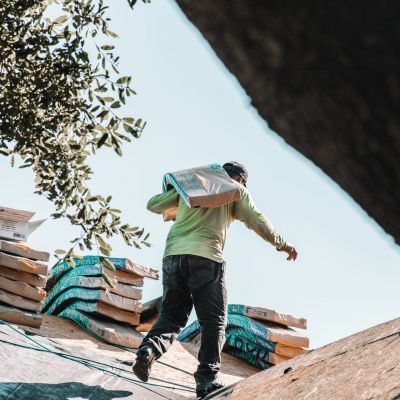 man on roof carrying materials